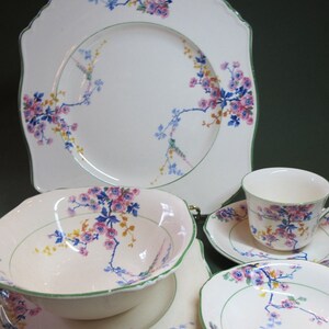 Puede incluir: Un juego de vajilla de porcelana vintage con flores con un delicado patrón floral rosa y azul con acentos verdes. El juego incluye un plato cuadrado, un tazón de sopa, un platillo y una taza de té.