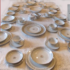 Pode incluir: Um conjunto completo de jantar em porcelana fina Mikasa Cotillion. O conjunto inclui pratos, tigelas, xícaras, pires e peças de servir. A porcelana branca apresenta um design floral com uma borda dourada. O conjunto inclui 55 peças e serve 8 pessoas.