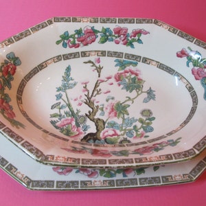 May include: A white octagonal serving dish with a green and gold border and a floral design. The dish has a smaller oval dish inside with a similar design.