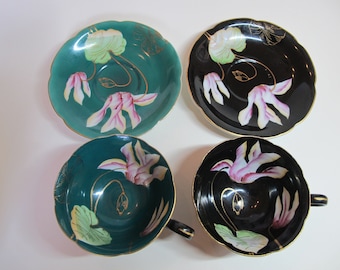 Puede incluir: Juego de cuatro tazas de té y platillos con diseños florales. Las tazas y los platillos están decorados con flores rosas y hojas verdes sobre un fondo negro y verde azulado.