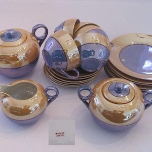 Peut inclure: Un service à thé vintage avec un design or et violet. L'ensemble comprend une théière, un pot à crème, un sucrier, quatre tasses et quatre soucoupes. L'ensemble est fabriqué au Japon.