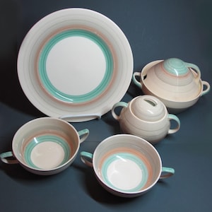 May include: A vintage set of ceramic dinnerware featuring a green and brown concentric circle design. The set includes a large dinner plate, a small bowl, a sugar bowl with a lid, and a serving bowl with a lid.