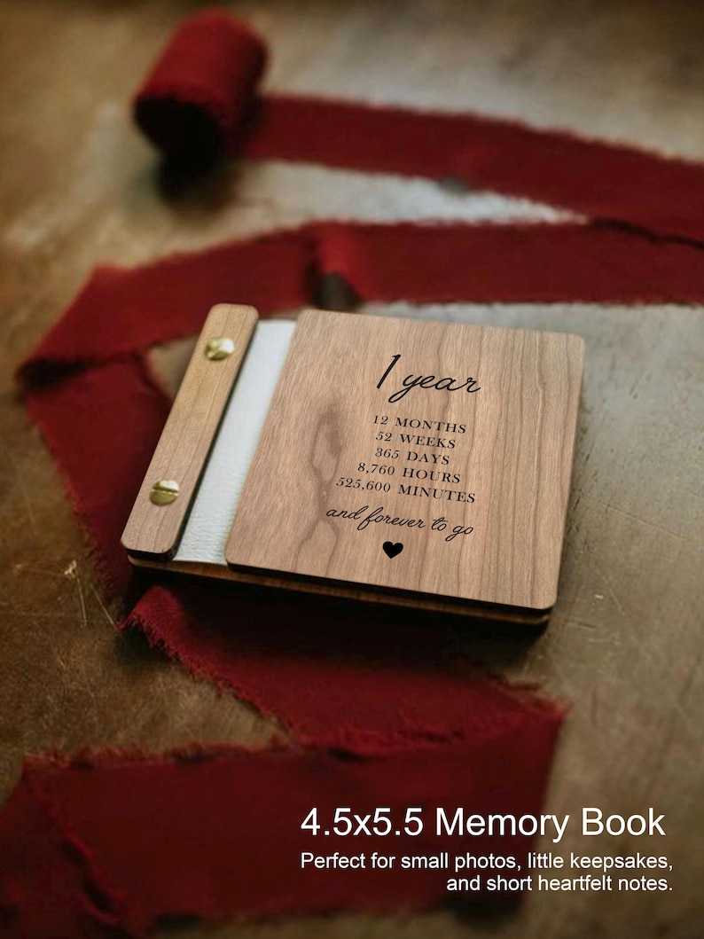 May include: A wooden memory book with the text "1 year" and time measurements. The book is 4.5 x 5.5 inches and has a light wood finish with a white spine. A red ribbon is draped around the book.