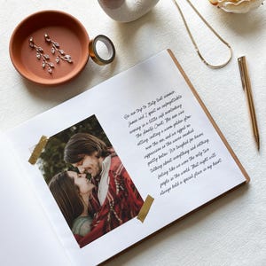 May include: An open scrapbook with a photo of a couple, accented with gold washi tape. A terracotta dish holds earrings. A gold pen, necklace, and decorative ring are also present. The page has handwritten text.