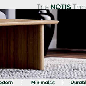 May include: The NOTIS Table, a modern and minimalist wooden table with a warm brown finish. The table's design features a rounded edge and a sturdy, durable construction. The image also includes a black vase and a gray rug.