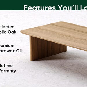 May include: A light brown rectangular coffee table made of solid oak. The table has a minimalist design with a flat top and a single leg on each end. The text "Features You'll Love" is at the top.