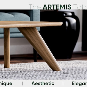May include: The Artemis Table, a modern wooden coffee table with a light wood finish. The table features a unique angled leg design and is set on a gray rug. The text at the top reads "The ARTEMIS Table". Below the table are the words "Unique | Aesthetic | Elegant".
