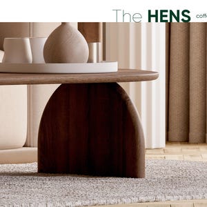 May include: A modern coffee table with a dark brown, arched base and a light brown tabletop. The table supports a white tray with decorative vases and cups. The text "The HENS coffee table" is visible in the upper right corner.