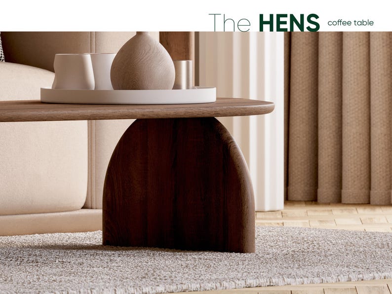 May include: A modern coffee table with a dark brown, arched base and a light brown tabletop. The table supports a white tray with decorative vases and cups. The text "The HENS coffee table" is visible in the upper right corner.