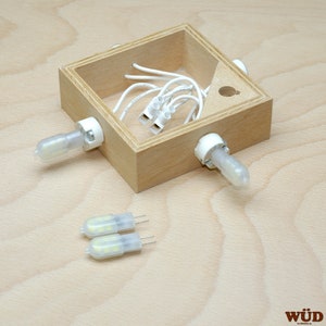 May include: A wooden box with a white wire and three white LED light bulbs. Two additional LED light bulbs are on the table next to the box.