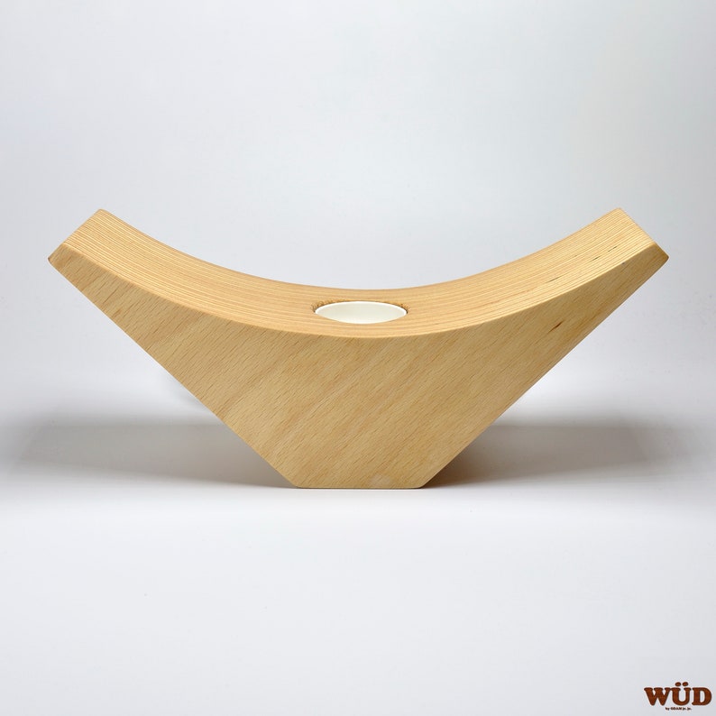 May include: A wooden candle holder shaped like a crescent moon with a small round opening in the center for a tea light candle.