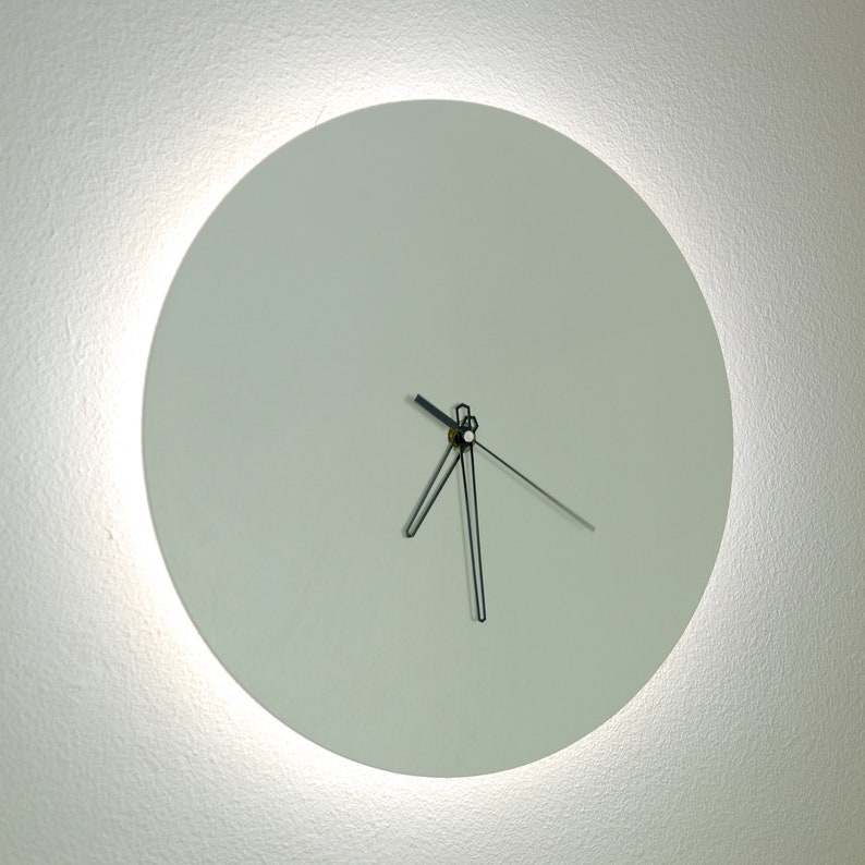 May include: A white round clock with black hands on a white wall.
