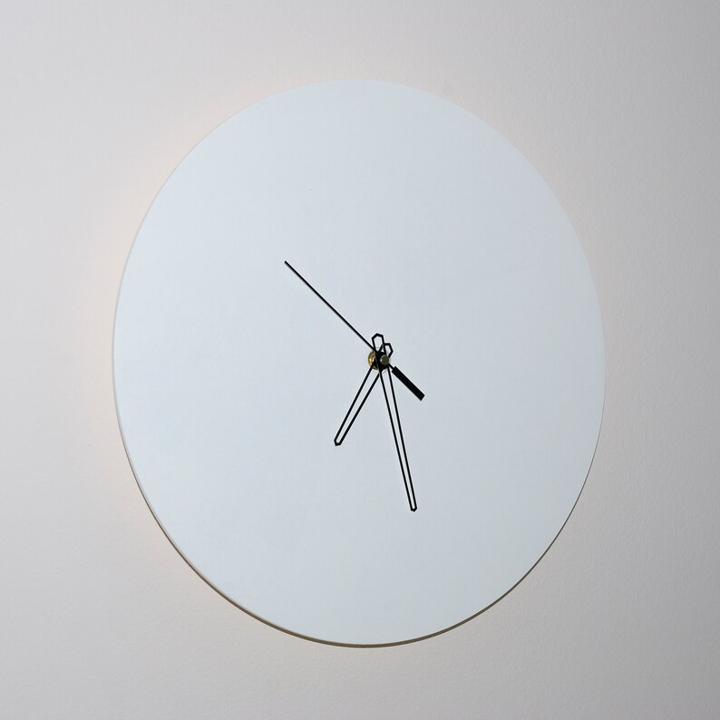 May include: A white round clock with black hands on a white wall.