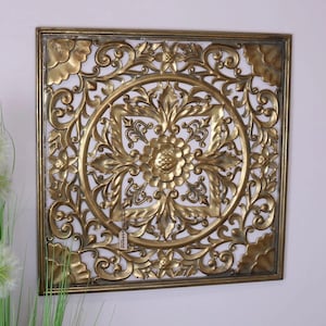 Könnte beinhalten: Goldene Wanddekoration aus Metall in quadratischer Form mit einem filigranen Blumendesign. Das Design verfügt über einen zentralen Kreis mit einem Blumenmuster und einem sich wiederholenden Muster aus Blättern und Blumen um den Rand.