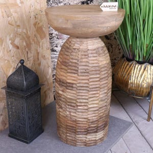 May include: A wooden side table with a unique, textured, honeycomb-like design. The table has a round top and a wide, sturdy base.