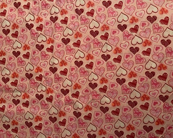 May include: A pink fabric with a repeating pattern of hearts in various shades of pink, red, and white. The hearts have different designs and textures.