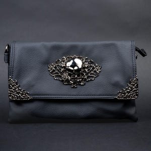 CHOK GothX vegan leather gothic bag styled on a dark goth style background. Bag is facing forward to show the intricate metal detailing of skulls and flowers.