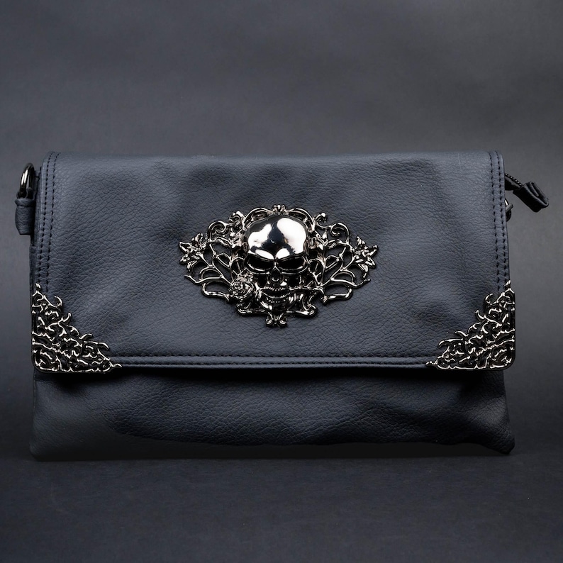 CHOK GothX vegan leather gothic bag styled on a dark goth style background. Bag is facing forward to show the intricate metal detailing of skulls and flowers.