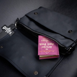 Open GOTHX gothic bag made with vegan leather showing inner compartment with a spellbook peeking out.