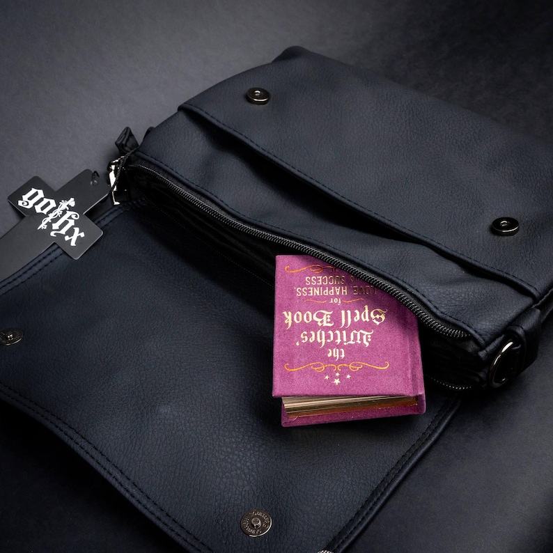 Open GOTHX gothic bag made with vegan leather showing inner compartment with a spellbook peeking out.