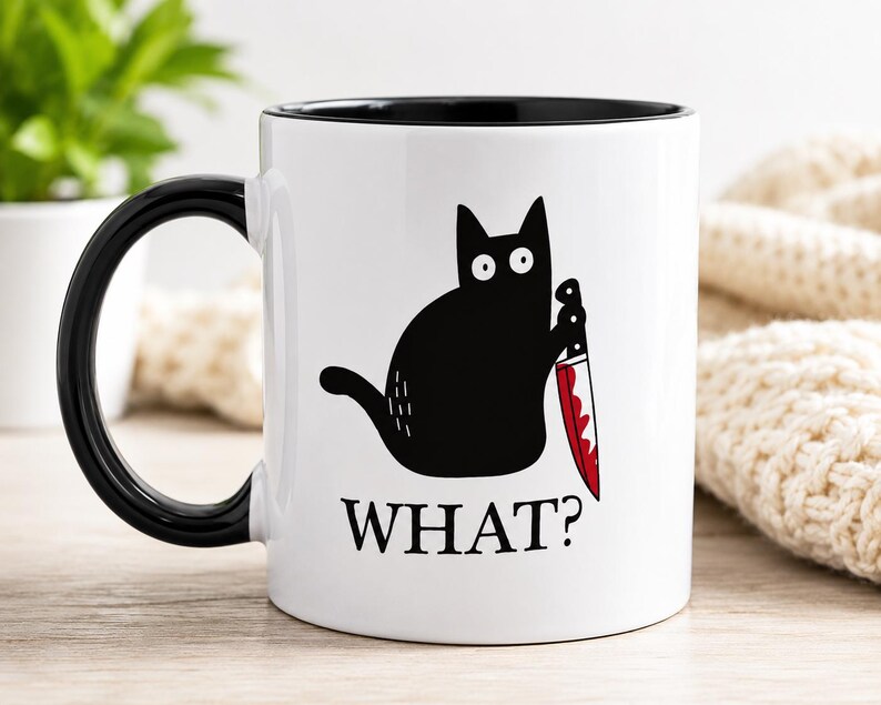 May include: A white ceramic mug with a black handle and interior. The front features a graphic of a black cat with wide eyes holding a knife with a red blade. Below the cat, the word WHAT? is printed in bold black capital letters.