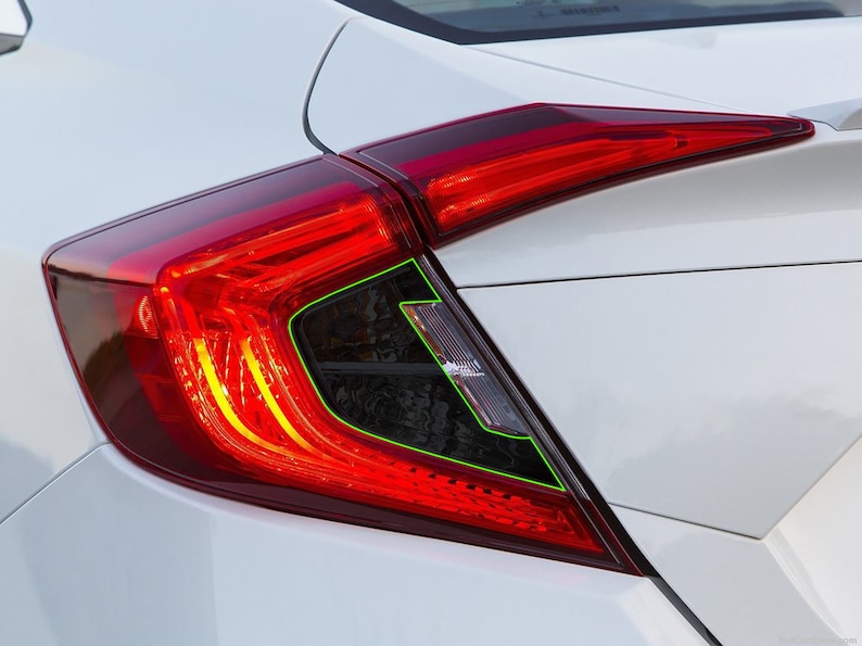 K&ouml;nnte beinhalten: Nahaufnahme eines roten R&uuml;cklichts an einem wei&szlig;en Auto. Das R&uuml;cklicht hat ein schwarzes Geh&auml;use und eine klare Linse. Das R&uuml;cklicht ist eingeschaltet und die Bremslichter leuchten.