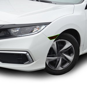 K&ouml;nnte beinhalten: Ein wei&szlig;er Honda Civic mit schwarzen Zierleisten um die Scheinwerfer und den K&uuml;hlergrill. Das Auto hat eine schwarze Frontsto&szlig;stange und schwarze R&auml;der mit silbernem Speichendesign.