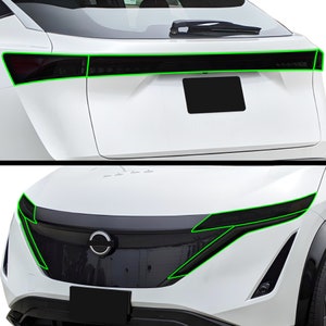 May include: A white car with black headlights and taillights. The car has a Nissan logo on the front.
