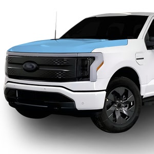 May include: A white pickup truck with a black grille and headlights. The hood of the truck is covered in a light blue protective film.