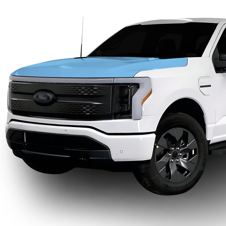 May include: A white pickup truck with a black grille and headlights. The hood of the truck is covered in a light blue protective film.