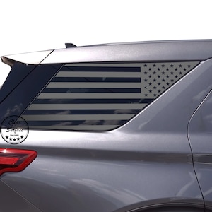May include: A grey SUV with a black and white American flag decal on the rear window. The decal is made of vinyl and is applied to the outside of the window. The decal is a popular way to show patriotism and support for the United States.