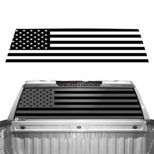 May include: Black and white American flag decal for a truck window. The decal is shown applied to the rear window of a pickup truck.
