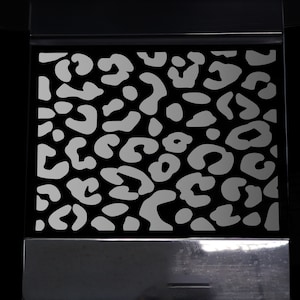 Peut inclure: Un motif léopard noir et blanc. L'imprimé est un motif répétitif de taches blanches sur un fond noir.