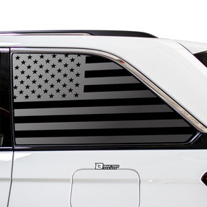 May include: A white SUV with a black and gray American flag decal on the rear passenger side window. The decal is a silhouette of the American flag with stars and stripes. The decal is on the window of a white SUV. The decal has the text "Bogar Tech Designs" on it.