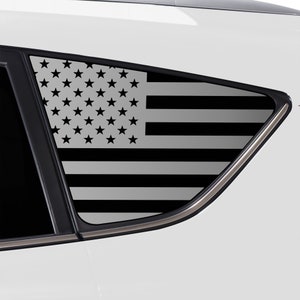 May include: A black and white American flag decal for a car window. The flag is displayed on a gray background.