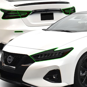 May include: A white Nissan Altima with blacked-out headlights and taillights. The car has a black grille with the Nissan logo in the centre.