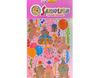 May include: A sheet of Sandy Lion sticker designs featuring birthday-themed teddy bears. The stickers include bears with party hats, balloons, and gifts. The background is pink with confetti and the Sandy Lion logo.
