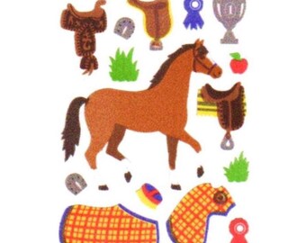 May include: A collection of equestrian-themed stickers featuring a brown horse, two saddles, a trophy, two horseshoes, two plaid horse blankets, a red apple, a blue rosette, a red rosette, a small brush, and two patches of green grass.