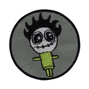 Könnte beinhalten: Ein runder, grauer gestickter Aufnäher mit einer schwarz-weißen Comicfigur. Die Figur hat einen grünen Körper, schwarze Haare und einen genähten Mund.