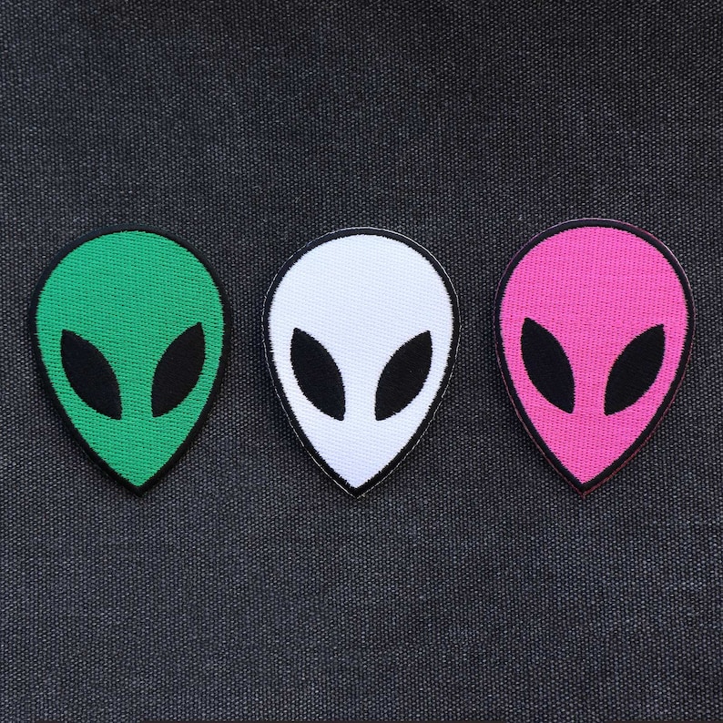 May include: Three alien head patches in green, white, and pink. Each patch has a black outline and black eyes.
