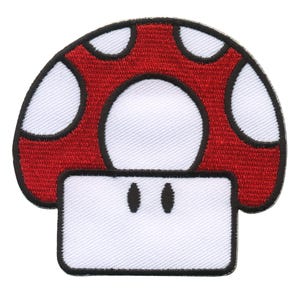 Puede incluir: Un parche en forma de hongo rojo y blanco con un tallo blanco y una tapa roja con manchas blancas. El parche está hecho de tela bordada.