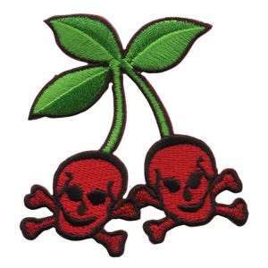 May include: Two red cherries with skull and crossbones designs, each with a green stem and leaf.