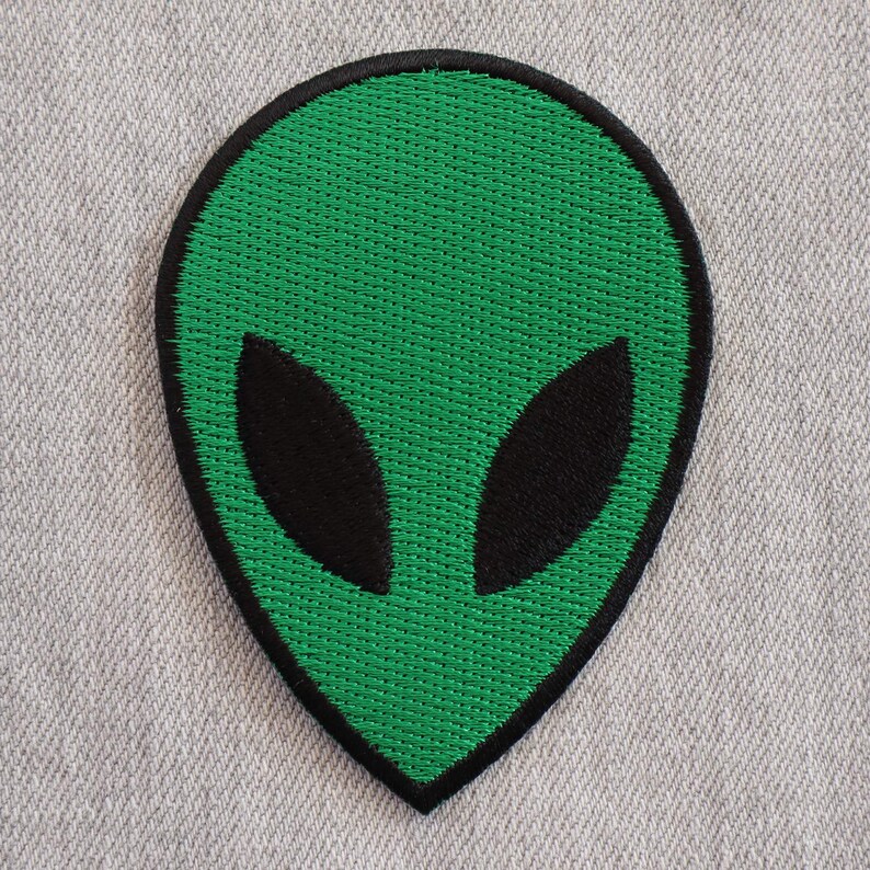 May include: Green alien head embroidered patch with black eyes.