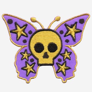 Könnte beinhalten: Lilafarbener Schmetterling mit einem gelben Totenkopf in der Mitte und goldenen Sternen auf den Flügeln.