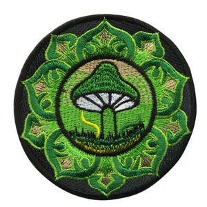 Può includere: Toppa ricamata verde con un fungo al centro circondato da un motivo a mandala verde e marrone.