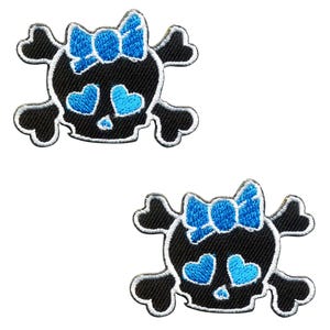 May include: Two black skull and crossbones patches with blue bows and blue heart eyes.