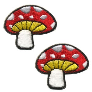 May include: Two red and white mushroom shaped embroidered iron-on patches. The mushrooms have white spots and a yellow underside.