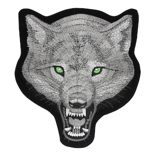 Puede incluir: Parche bordado para planchar de la cabeza de un lobo gruñendo con ojos verdes. El pelaje del lobo es gris y el fondo es negro.