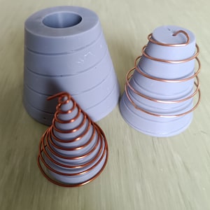 May include: Three gray silicone molds for making resin crafts. Two of the molds are cone-shaped with a copper wire coil inside. The third mold is a larger cone shape with a circular opening at the top.