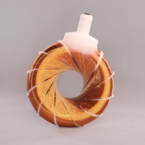 Pode incluir: Uma bobina de cor cobre com um componente de plástico branco. A bobina é circular com uma abertura central. Faixas de plástico branco prendem as camadas da bobina. O objeto está sobre um fundo cinza neutro.